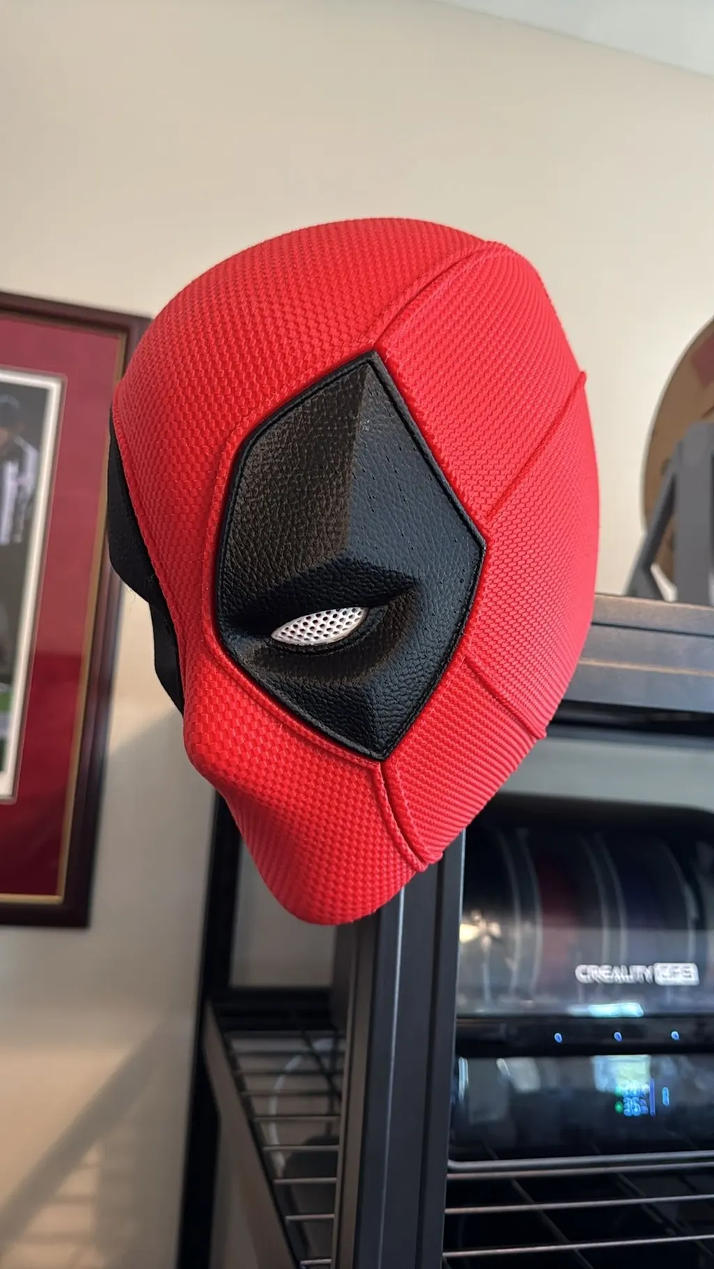 Red and black comic antihero mask with a woven texture, three-quarter view