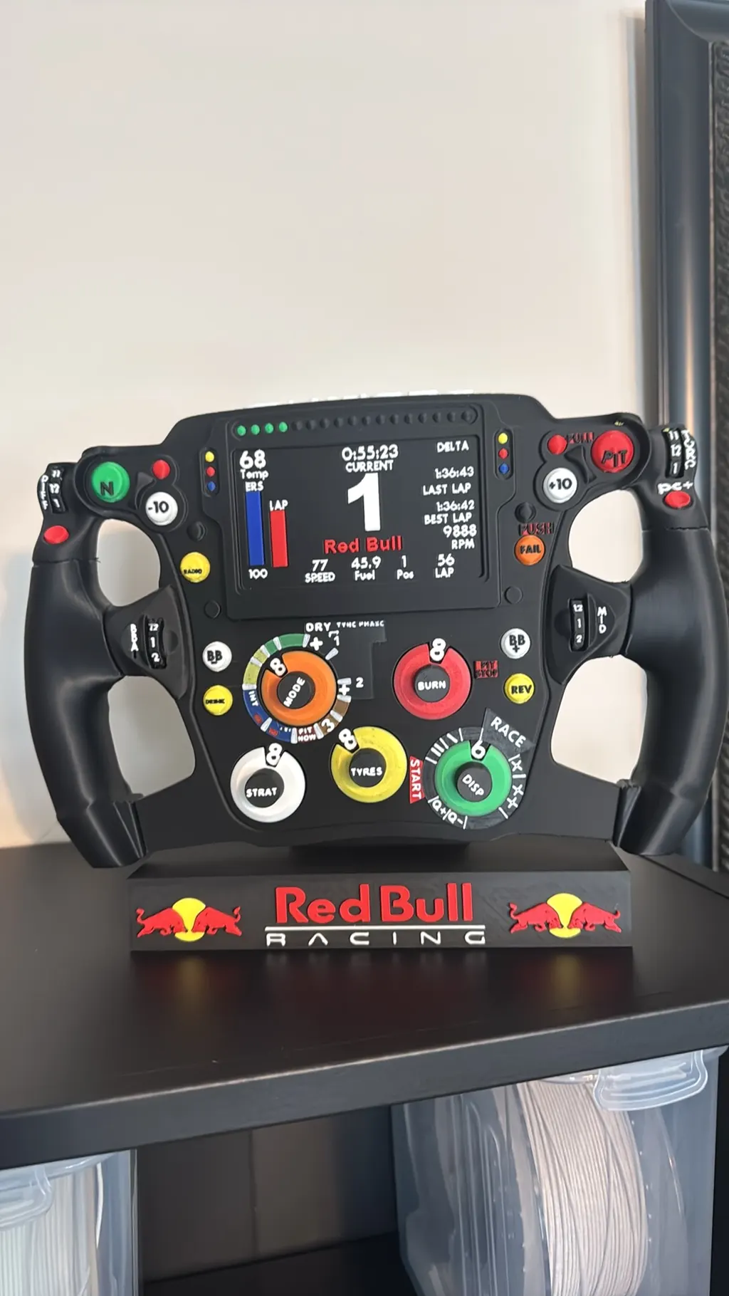 Full-size multicolor replica of a Formula One steering wheel on a display stand