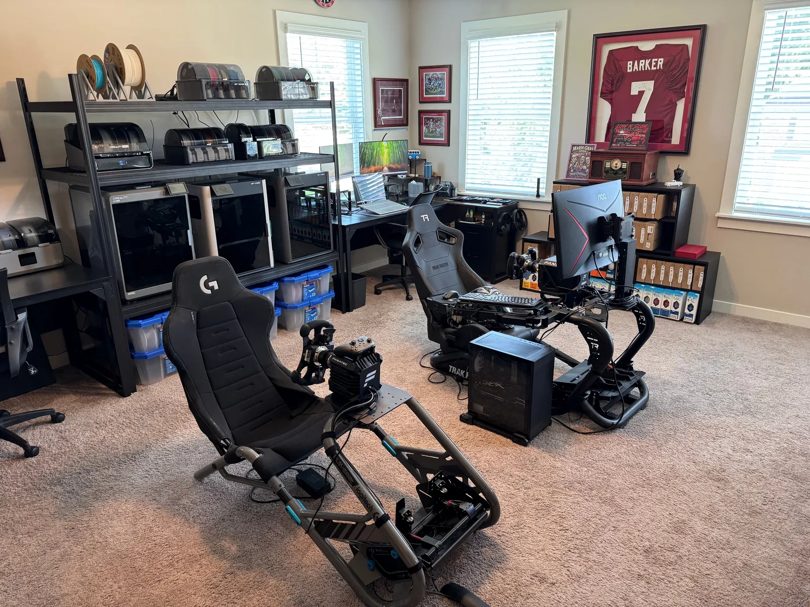 The KirkWorks3D studio in Helena: three printers on a rack beside shelves of filament, two racing simulators and a desk.