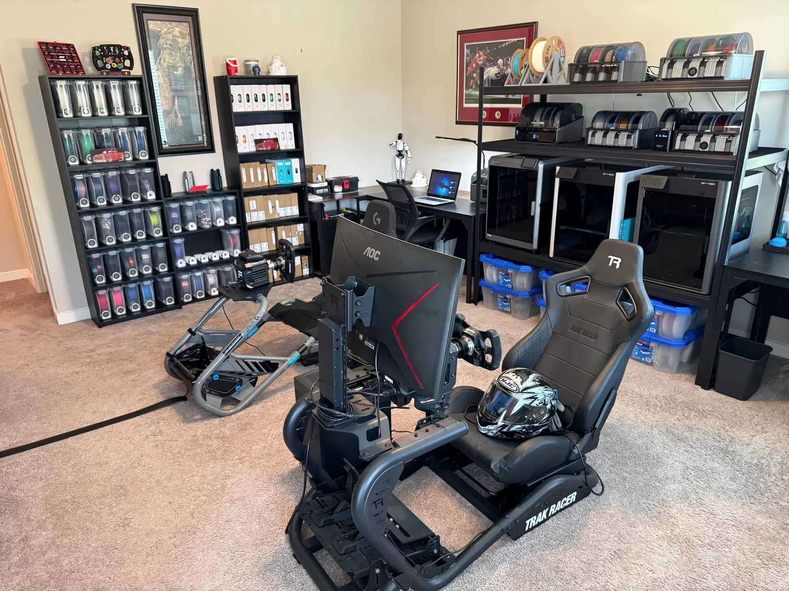 The KirkWorks3D production room: the printer rack, shelves of filament and two racing simulators.